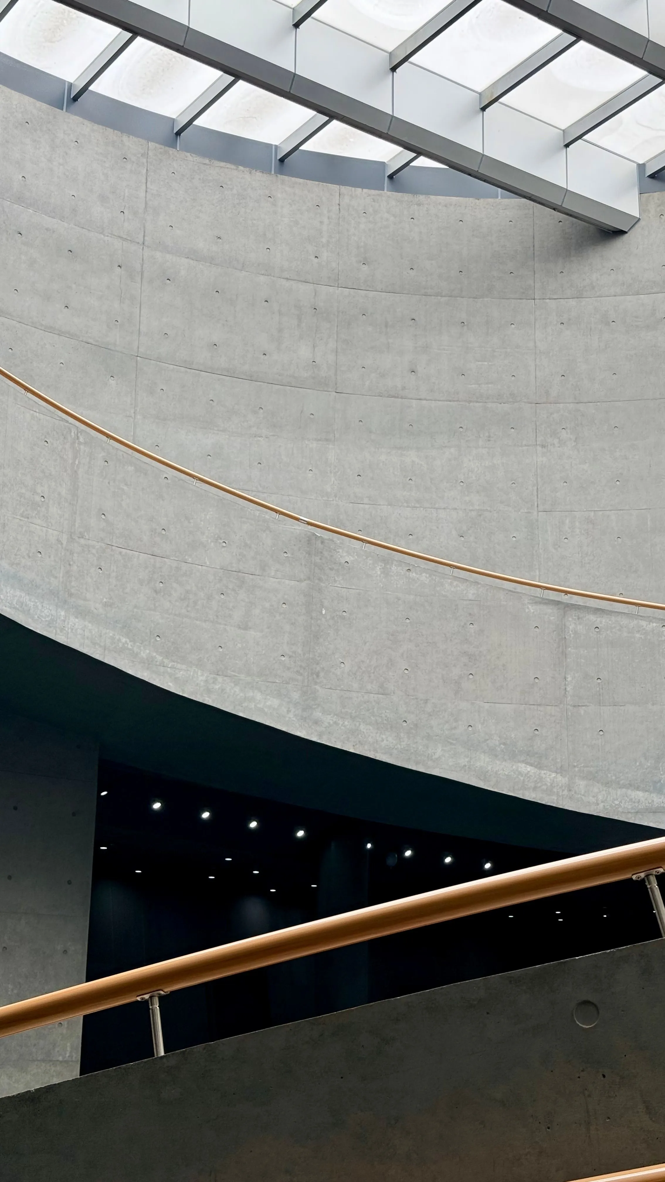 A curved concrete interior with a thin bronze line and a skylight.