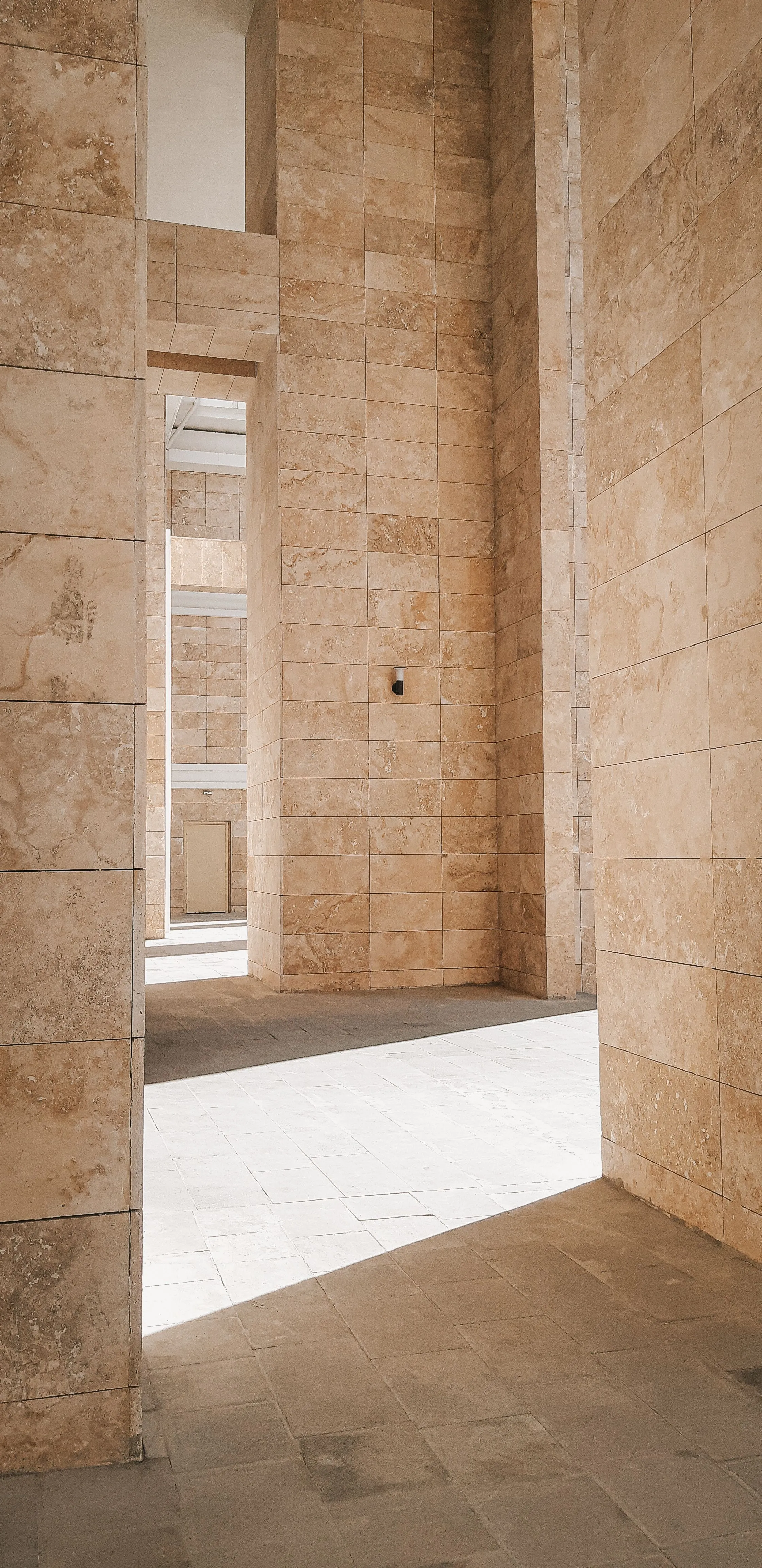 A stone colonnade with afternoon light falling across the columns.